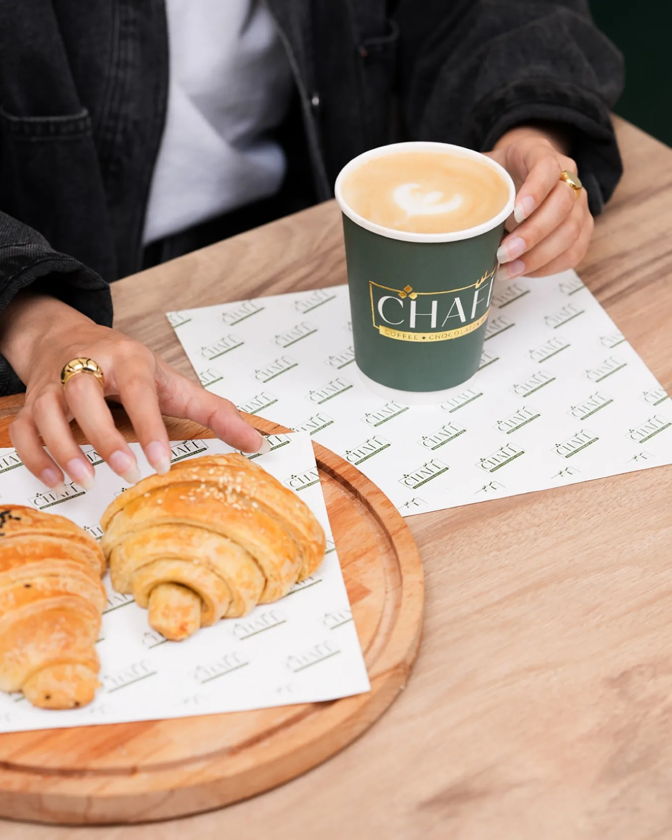 Butter croissants on a board with a green CHAFÉ cup