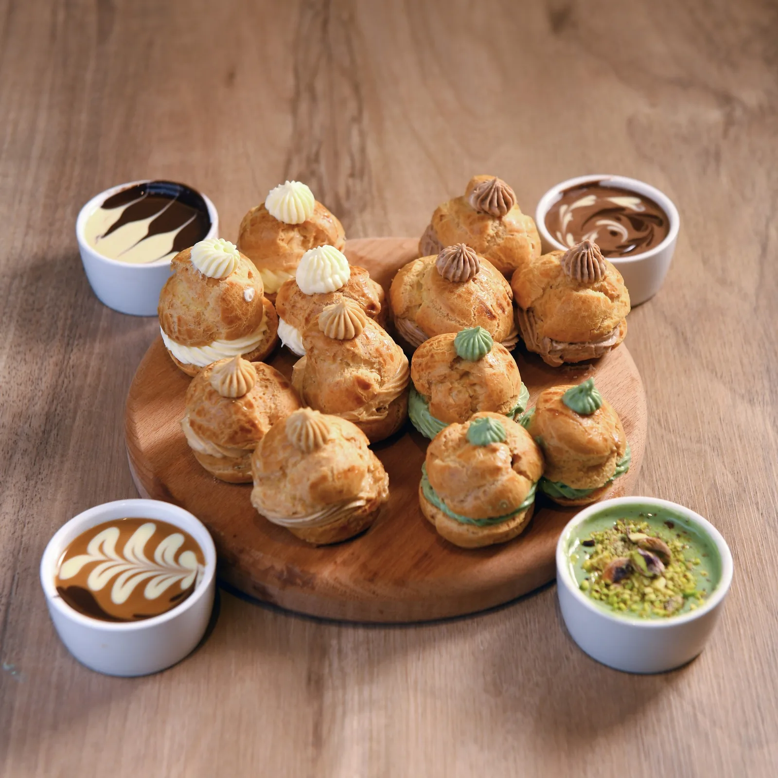 A board of profiteroles with chocolate and pistachio dips