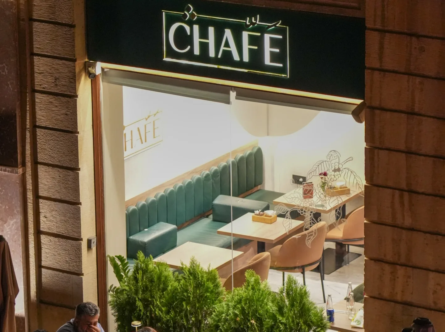 The CHAFÉ sign above the window, green velvet banquettes inside