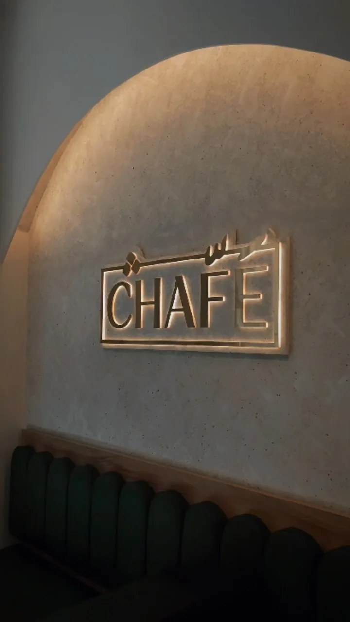 The CHAFÉ wordmark in brushed gold on a plaster wall