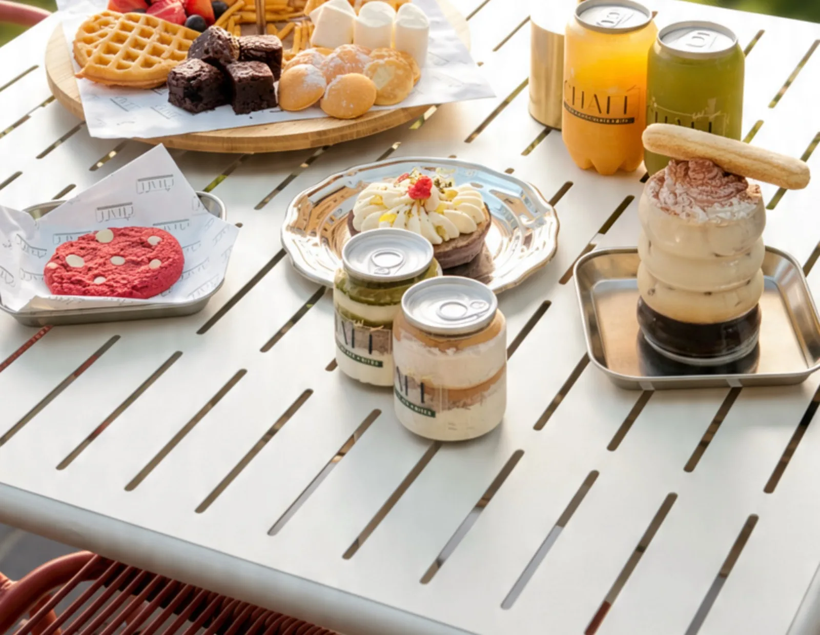 A terrace table of fondue, dessert cups, juices and tiramisu
